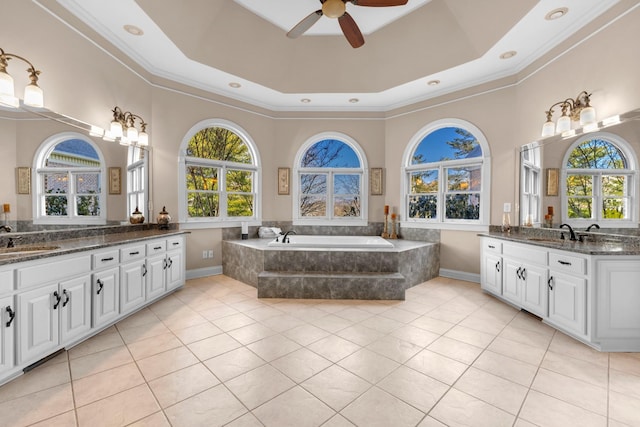 bathroom featuring tile patterned flooring, a tray ceiling, two vanities, and a sink