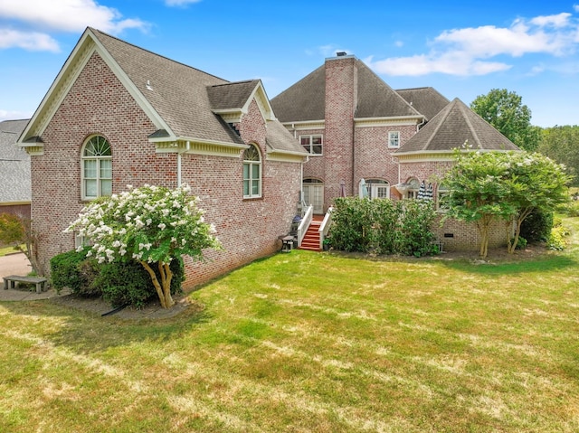 back of property featuring roof with shingles, a yard, a chimney, crawl space, and brick siding