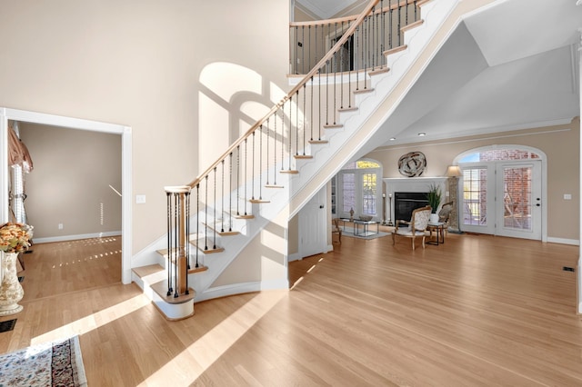 stairs with a fireplace, baseboards, a towering ceiling, and wood finished floors