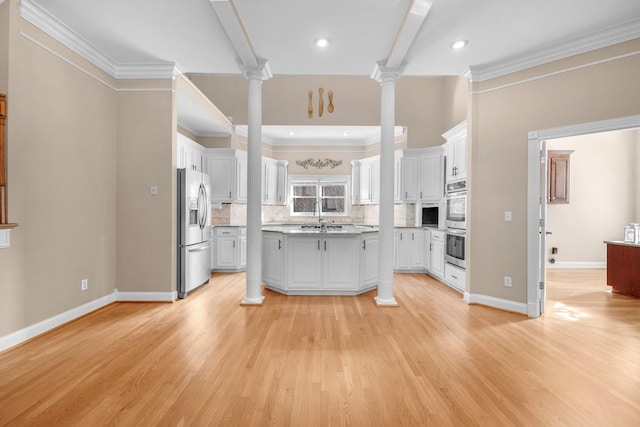 kitchen featuring decorative backsplash, decorative columns, white cabinetry, and stainless steel appliances