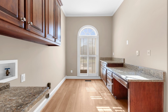 clothes washing area with baseboards, ornamental molding, hookup for a washing machine, light wood-style floors, and cabinet space