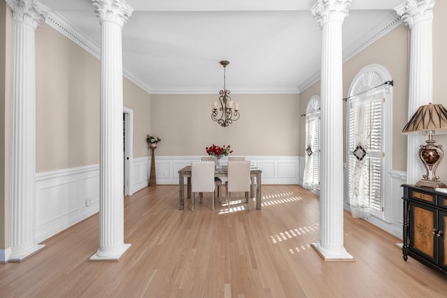 dining area with light wood finished floors, an inviting chandelier, ornate columns, and ornamental molding