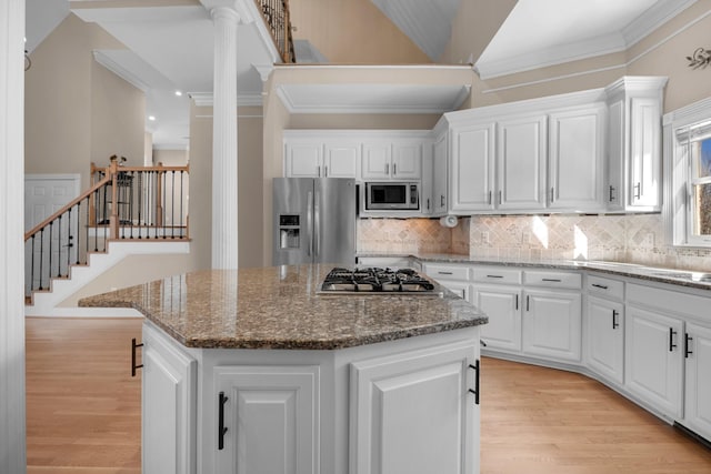 kitchen featuring light wood-type flooring, stainless steel appliances, white cabinets, and ornate columns