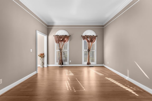 unfurnished room featuring crown molding, baseboards, and wood finished floors