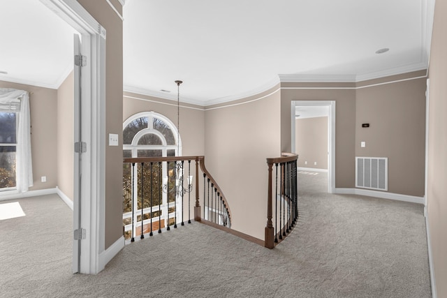 hallway with visible vents, baseboards, ornamental molding, carpet flooring, and an upstairs landing