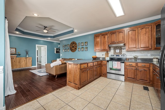 kitchen featuring stainless steel electric range oven, a raised ceiling, kitchen peninsula, and light tile patterned floors