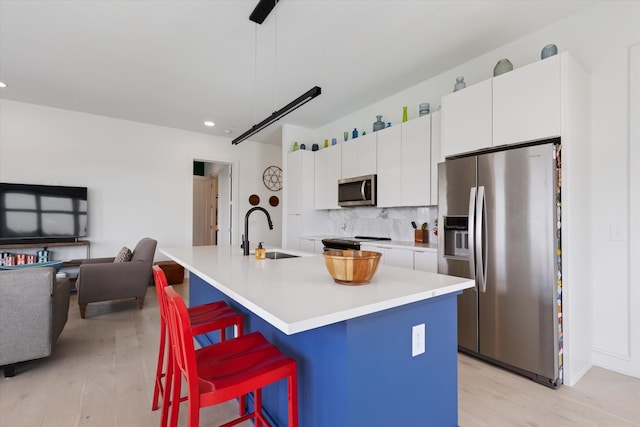 kitchen featuring appliances with stainless steel finishes, a kitchen island with sink, sink, and decorative light fixtures