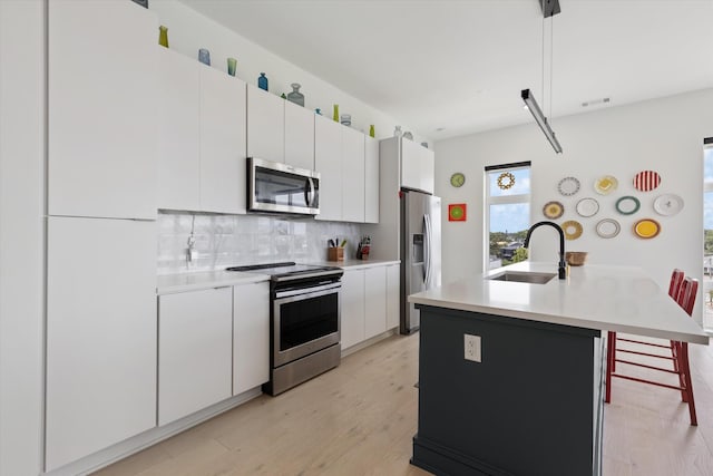 kitchen with pendant lighting, white cabinetry, an island with sink, sink, and stainless steel appliances