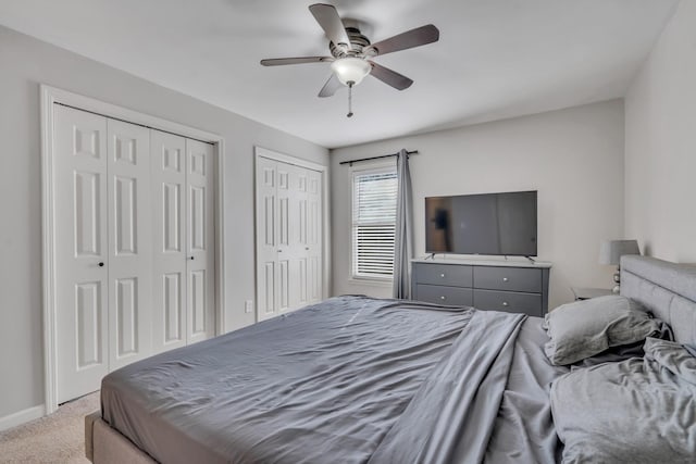 bedroom with ceiling fan, multiple closets, and carpet flooring