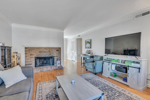 living room featuring hardwood / wood-style flooring, crown molding, and a brick fireplace