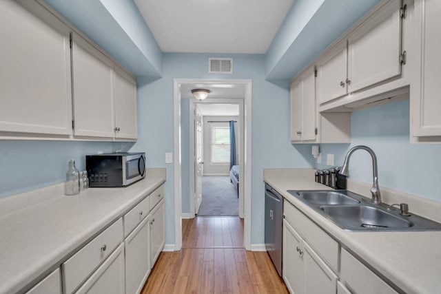 kitchen with light wood-type flooring, stainless steel appliances, sink, and white cabinets