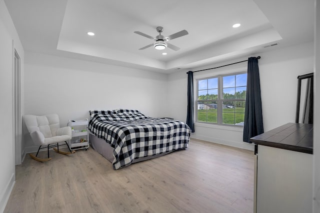 bedroom with a tray ceiling and light hardwood / wood-style floors