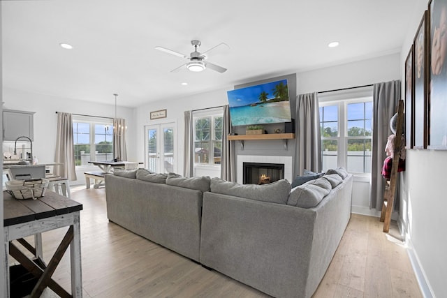 living room with ceiling fan with notable chandelier and light wood-type flooring