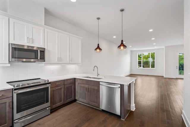 kitchen featuring tasteful backsplash, sink, white cabinets, hanging light fixtures, and stainless steel appliances