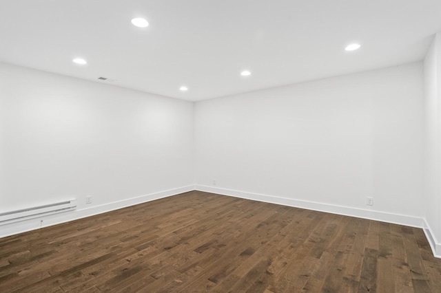 empty room with dark hardwood / wood-style flooring and a baseboard radiator