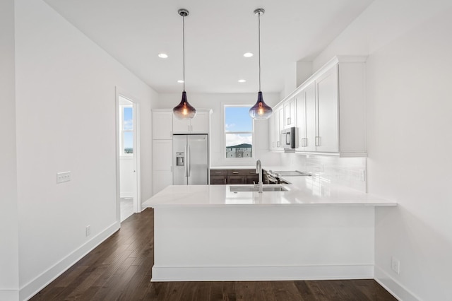 kitchen featuring sink, kitchen peninsula, pendant lighting, stainless steel appliances, and white cabinets