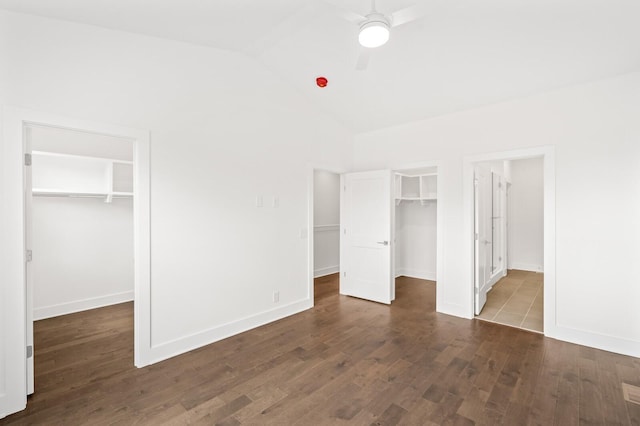 unfurnished bedroom with ceiling fan, high vaulted ceiling, dark hardwood / wood-style floors, a walk in closet, and a closet