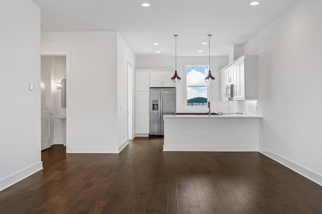 kitchen with dark wood-type flooring, appliances with stainless steel finishes, white cabinetry, decorative light fixtures, and kitchen peninsula