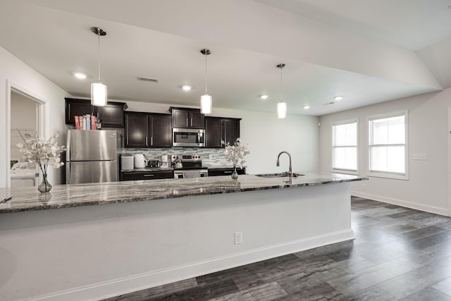 kitchen featuring pendant lighting, sink, light stone counters, and stainless steel appliances