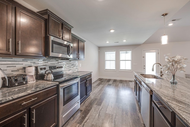 kitchen with sink, appliances with stainless steel finishes, backsplash, dark brown cabinetry, and stone countertops