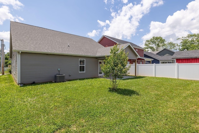 back of house featuring central AC unit and a lawn