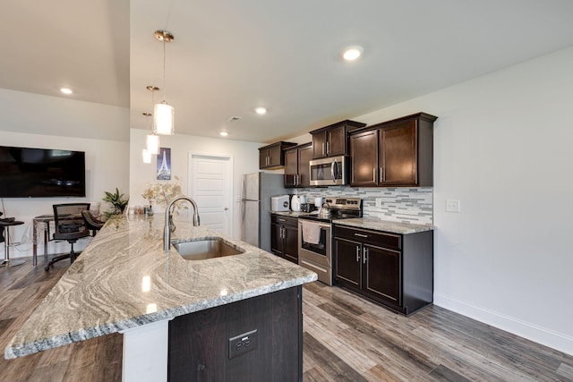 kitchen featuring sink, backsplash, dark brown cabinets, stainless steel appliances, and decorative light fixtures