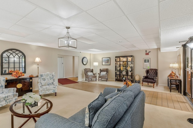 tiled living room featuring an inviting chandelier and a paneled ceiling