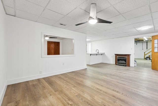 unfurnished living room with wine cooler, sink, a paneled ceiling, wood-type flooring, and ceiling fan