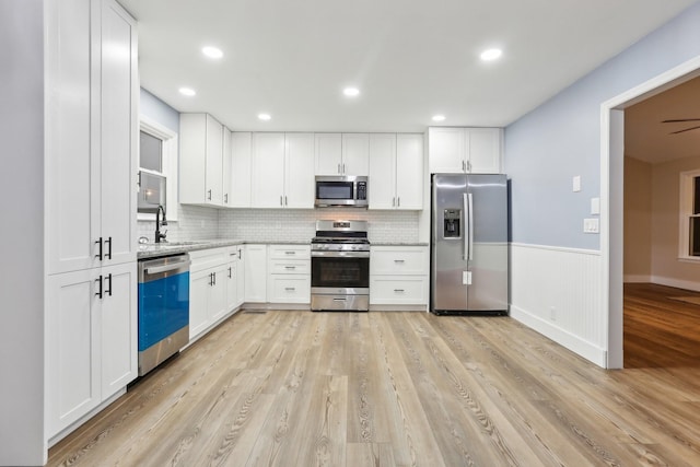 kitchen with stainless steel appliances, light hardwood / wood-style floors, sink, and white cabinets