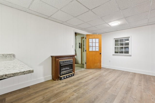 unfurnished living room featuring heating unit, a paneled ceiling, and light hardwood / wood-style flooring