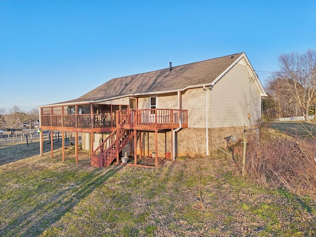 rear view of property featuring a wooden deck, a yard, and a sunroom