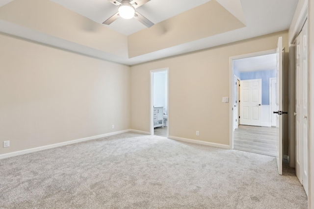 carpeted empty room featuring ceiling fan and a tray ceiling