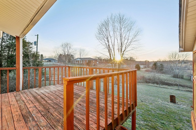 deck at dusk featuring a lawn