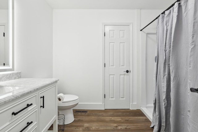 bathroom featuring wood-type flooring, toilet, a shower with shower curtain, and vanity