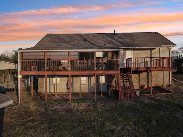 back house at dusk featuring a wooden deck and a yard