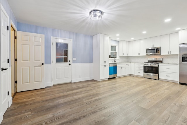 kitchen with backsplash, light hardwood / wood-style flooring, stainless steel appliances, and white cabinets