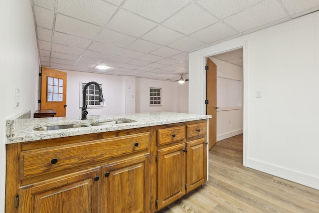 kitchen featuring light stone counters, sink, light hardwood / wood-style flooring, and a drop ceiling