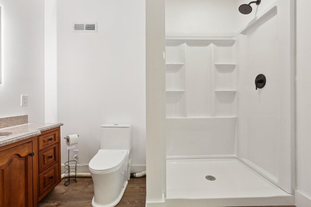 bathroom featuring a shower, wood-type flooring, vanity, and toilet