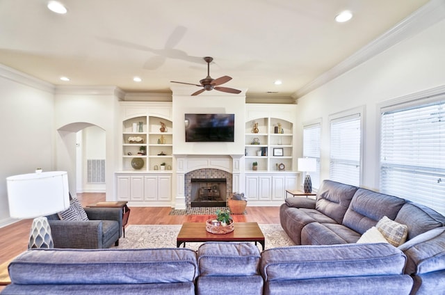 living room featuring built in features, ornamental molding, and light hardwood / wood-style floors