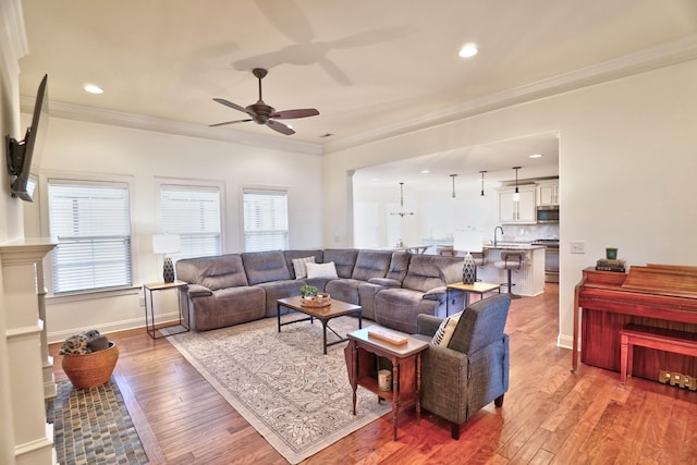 living room with ornamental molding, plenty of natural light, sink, and light hardwood / wood-style flooring