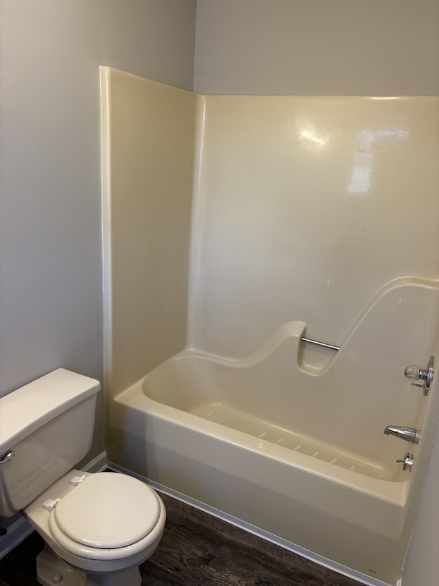 bathroom with wood-type flooring, washtub / shower combination, and toilet