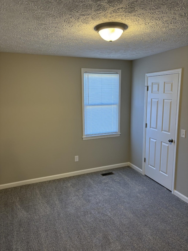 empty room with a textured ceiling and dark colored carpet