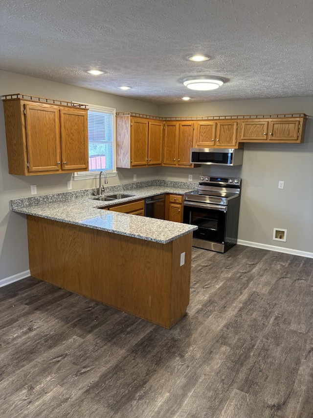 kitchen with sink, dark wood-type flooring, appliances with stainless steel finishes, a textured ceiling, and kitchen peninsula