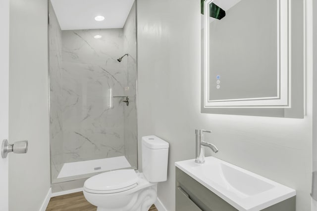 bathroom with vanity, hardwood / wood-style floors, toilet, and tiled shower