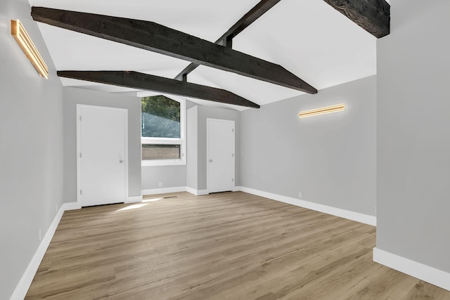 unfurnished living room featuring light hardwood / wood-style flooring and vaulted ceiling with beams