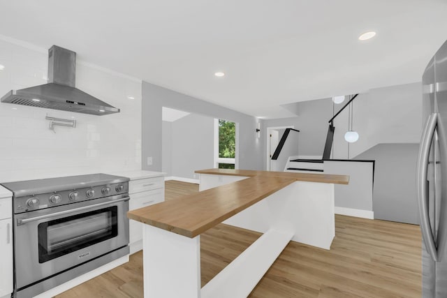 kitchen with appliances with stainless steel finishes, butcher block countertops, white cabinetry, decorative backsplash, and island exhaust hood