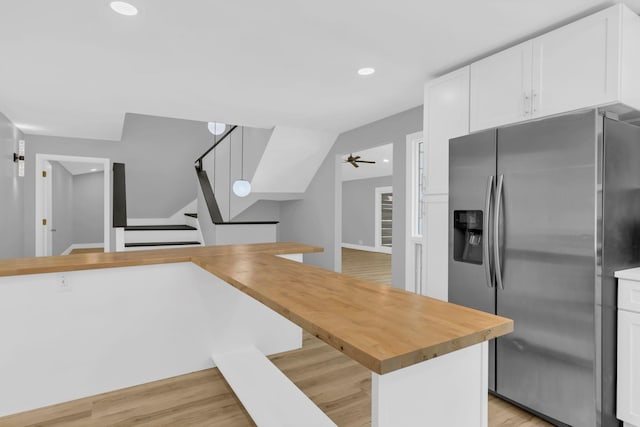 kitchen with stainless steel refrigerator with ice dispenser, butcher block counters, white cabinetry, light wood-type flooring, and kitchen peninsula