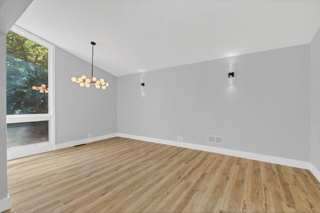 spare room with lofted ceiling, a notable chandelier, and light hardwood / wood-style flooring