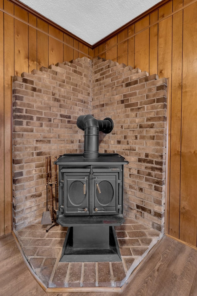 room details with hardwood / wood-style floors, wooden walls, a textured ceiling, and a wood stove