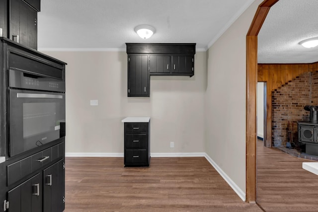 kitchen featuring dark wood-type flooring, black oven, a textured ceiling, and a wood stove